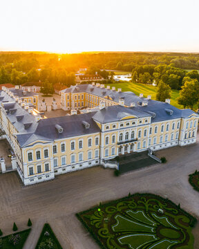 Pilsrundale, Latvia - 04 July 2025: Aerial view of Rundale Palace Museum featuring its baroque architecture, yellow facade, and intricate formal gardens during a golden sunset.
