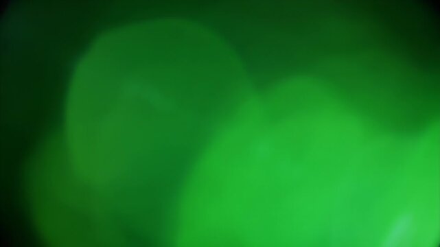 A soft focus abstract image featuring glowing green light shapes against a dark background, creating a dreamy and ethereal visual effect.