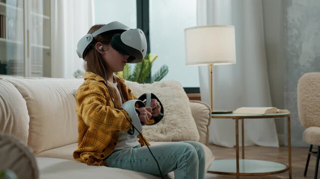 Little schoolgirl chid girl in vr helmet playing game with online technology cyberspace metaverse at living room in apartment kid daughter gamer gadget addict gaming addiction with virtual reality