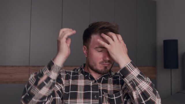 A man does hair styling at home, he adjusts his hair with his hands trying to achieve the perfect hairstyle.