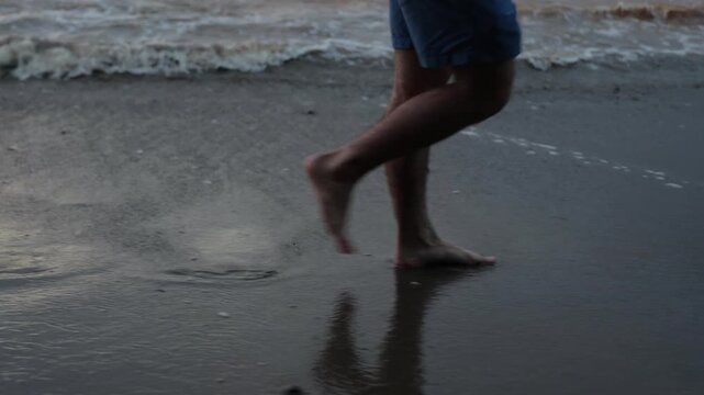 Close-up cinematic shot of barefoot footsteps walking along wet tropical beach sand with
smooth lateral dolly movement.