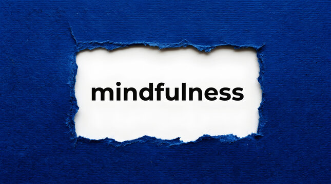 Torn blue paper reveals the word mindfulness in black text ripped white