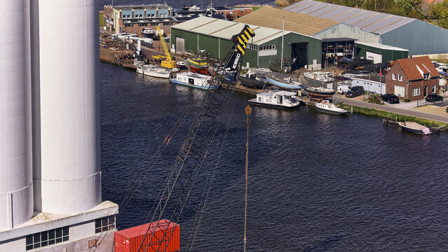 Wormerveer, Netherlands - 28 April 2026: Aerial view of a ship repair yard at the Zaan river with boats and a large crane, seen from the Meneba flourmill silo.