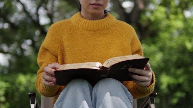 A young woman sits reading the Bible, learning about God during her quiet time seeking peaceful healing through love and His holy word.