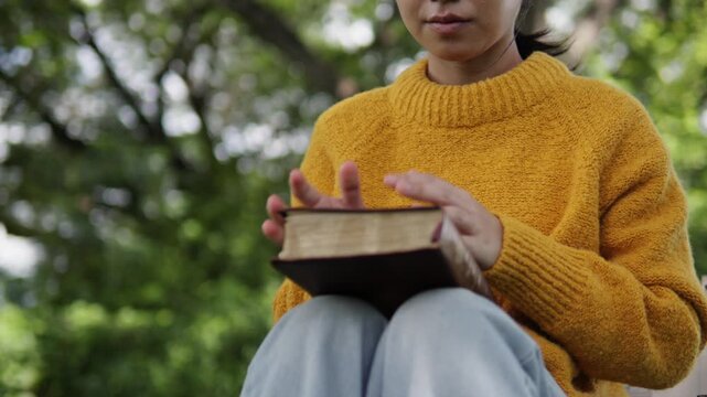 A young woman sits praying to God with her Bible, asking for a peaceful healing in her life healed by love and His holy word