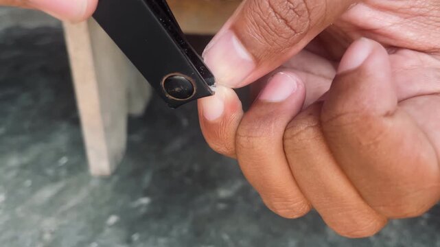 Close up of trimming pinky fingernail with nail clippers, personal grooming activity highlighting hygiene, self care and hand maintenance routine.