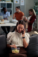Obraz premium Businesswoman multitasking having healthy office lunch while talking on phone