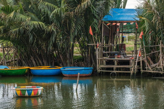 Round basket boats moored next to a wooden pier by water coconut palms