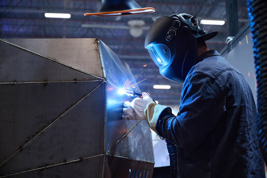 A welder works with a large metal structure at a mechanical engineering plant.