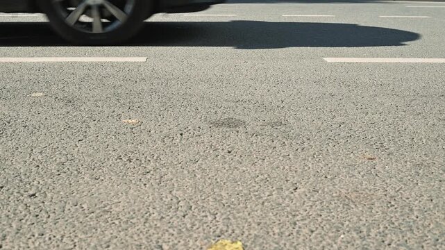 A car travels along an asphalt road showing close-up shots of the tire rolling over the surface. The focus is on the movement and texture of the road as the vehicle accelerates