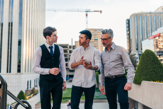 Three businessmen discussing work using smartphone in city