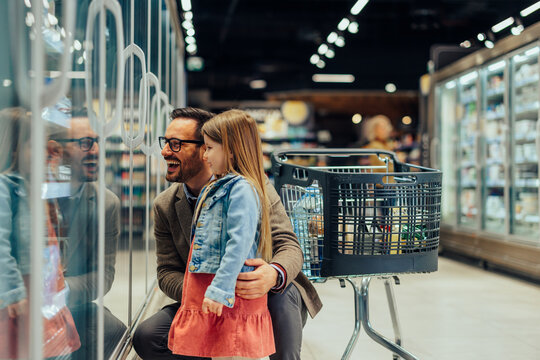 Father and daughter laughing while shopping in supermarket