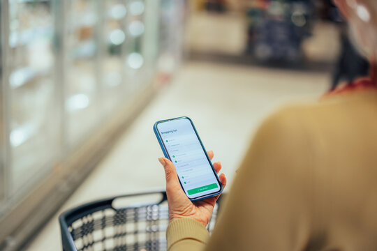 Person checking shopping list app on smart phone in supermarket