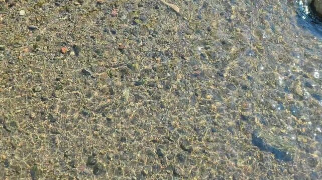 Crystal Clear River Water Over Pebble Stone Bed Texture Close Up in Indonesia