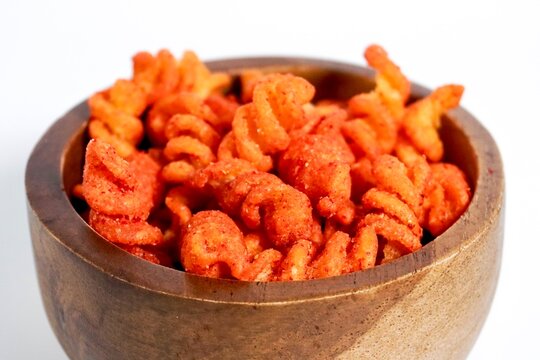 Close up spicy makaroni spiral indonesian snack in wooden bowl isolated on horizontal white background.
