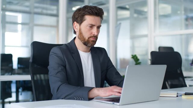 Focused Caucasian middle-aged business man typing laptop thinking looking in screen pondering online job task mature businessman think look in computer male agent work in internet network in office