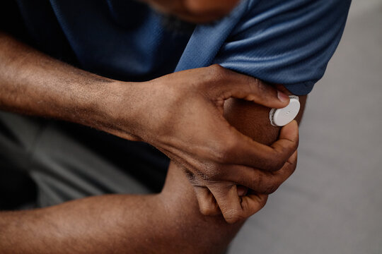 Close up of Black man adjusting glucose monitor on upper arm, managing diabetes and tracking health data. Ideal for healthcare campaigns, chronic condition awareness, telehealth