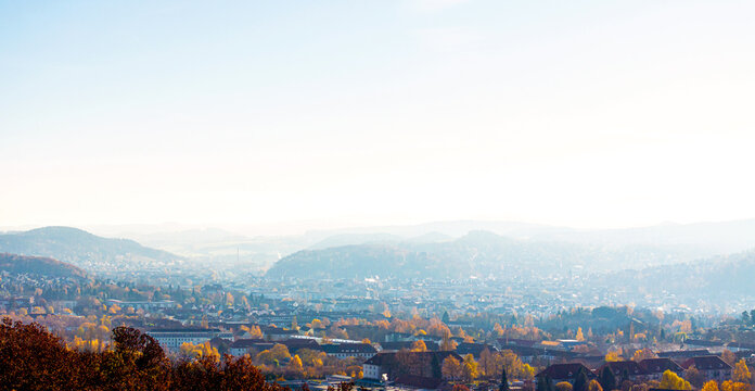 Aerial view of the historic city nestled in a valley with colorful autumn trees and rolling hills under a bright hazy sky Eisenach, Thuringia, Germany.