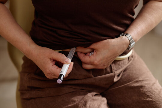 Close up of woman injecting abdomen with insulin pen, managing diabetes treatment at home. Ideal for healthcare campaigns, chronic disease management, patient education