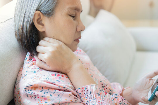 Asian matue woman using hand to massage her neck, taking pressure on the spine, neck fatigue, muscle pain