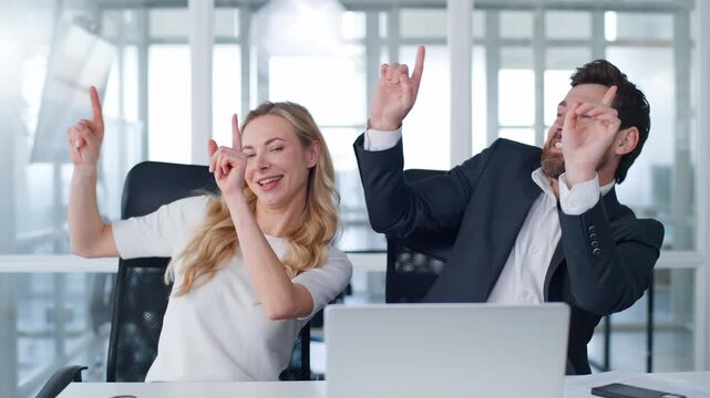 Two business partners dancing at office table Caucasian middle-aged businessman with businesswoman dance together in company working laptop celebrating adult woman senior mature man having fun work