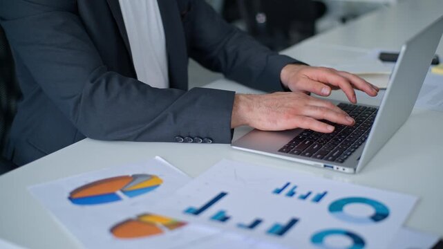 Cropped view male hands typing laptop checking data in diagram unrecognizable Caucasian business man working with computer with corporate documents stats financial results using technology in office