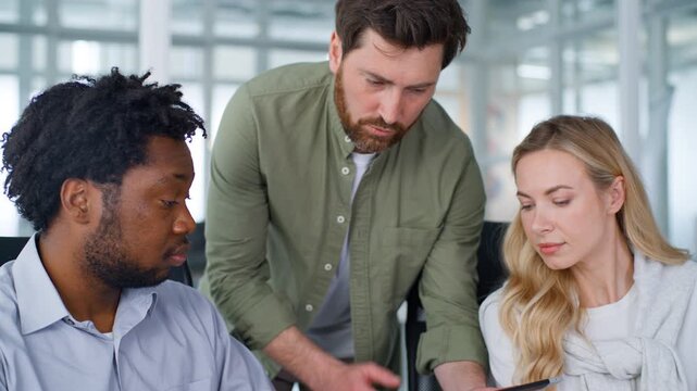 Team three multiracial business managers upset talking with bad result Caucasian boss showing mistake digital tablet portable computer African men woman interns frustrated with failure talk in office