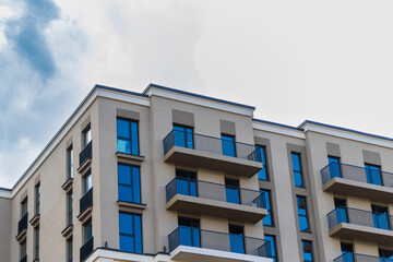 Fototapeta premium Modern apartment building facade with balconies against a blue sky. Urban