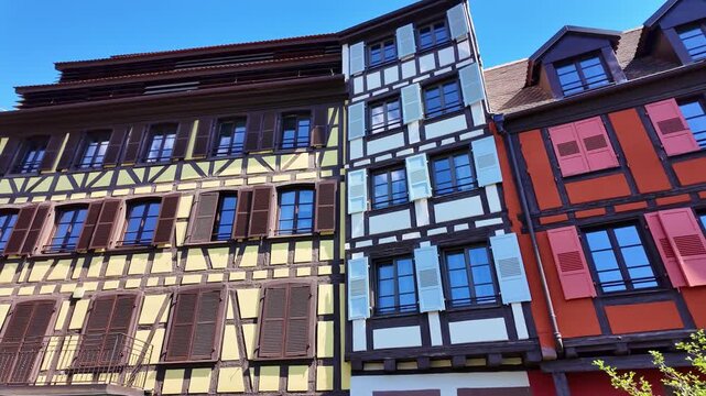 Low-angle pan across vivid Alsatian timber-framed facades, colored shutters and lilac flowers.