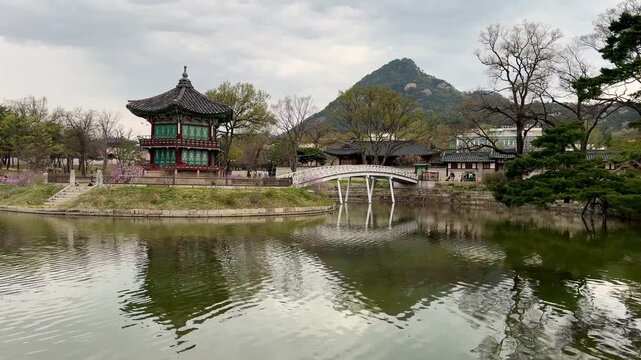 Hyangwonjeong Pavilion is an octagonal pavilion set on a lotus pond, connected by a slender arched bridge, showcasing royal architecture reflected in the surrounding water.