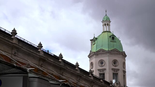 Pale green domed cupola of a historic market hall rises above the sloping roofline under heavy clouds.