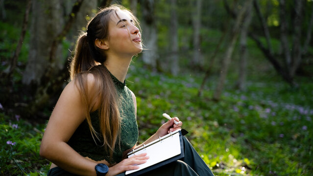 Grateful female reflecting on thoughts and dreams while journaling outdoors in nature. Self-care, mindfulness practice and positive lifestyle.
