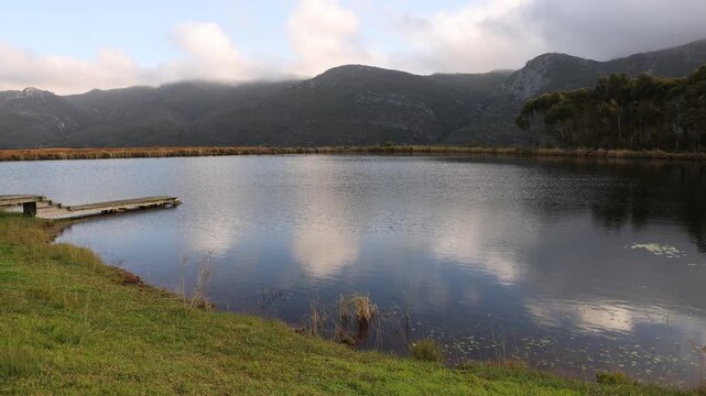 pond , grass , trees and Klein Mountains, Stanford, South Africa as the morning fog burns off