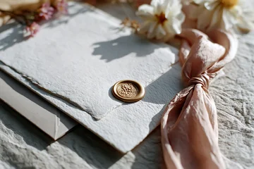 Elegant handmade wedding invitation suite laid out with envelope, wax seal, ribbon and dried blooms. Romantic stationery and celebration themes - wedding, romance, Valentine's Day, anniversary. © Magryt