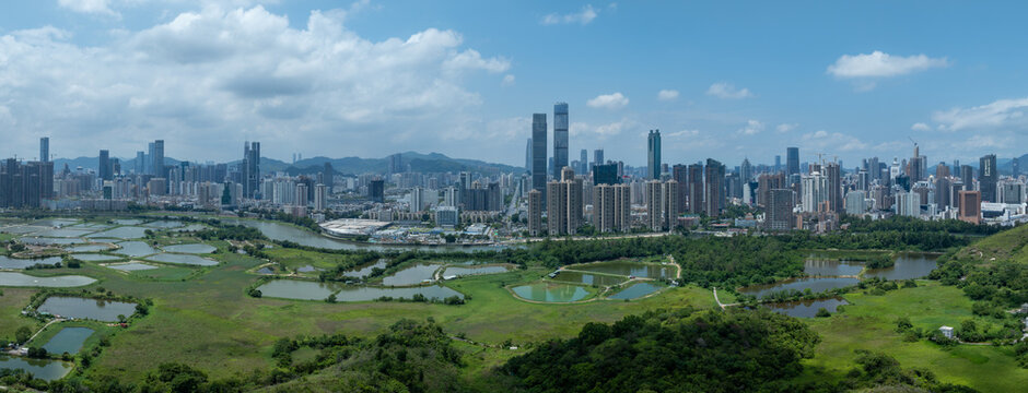 Aerial view of rural green fields with fish ponds on Hong Kong and the skylines of Shenzhen