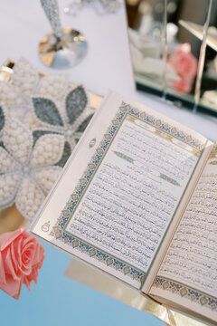 Open Quran with decorative border and pink rose
