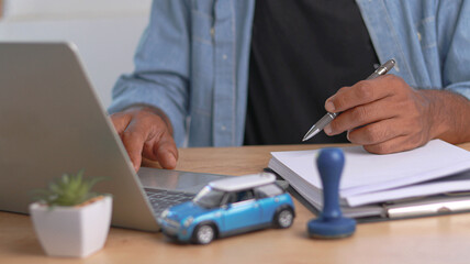 Close-up of a professional reviewing vehicle insurance or auto loan documents while working on a...