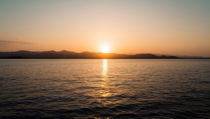 Obraz premium Sunset over calm water with distant mountains in view