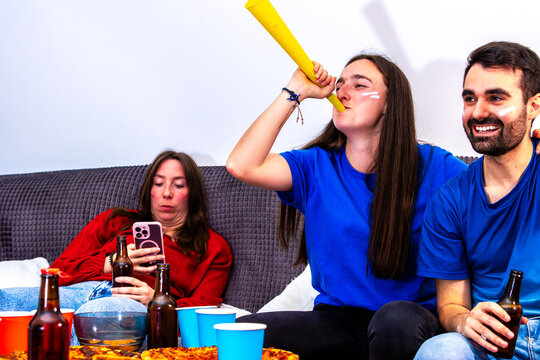 Friends watching international football tournament at home, celebrating a goal
