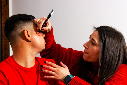 Couple friends preparing for a soccer match, painting face for team support