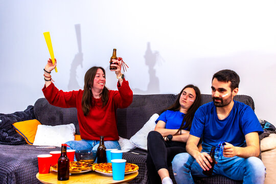 Football fans watching an international tournament at home, one celebrating victory
