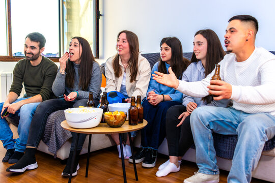 Friends watching a soccer match at home, celebrating sports and friendship