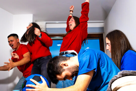 Friends experiencing mixed emotions while watching a football game on television at home