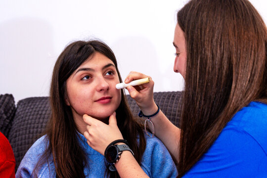 Friends painting face for football match, celebrating international tournament at home
