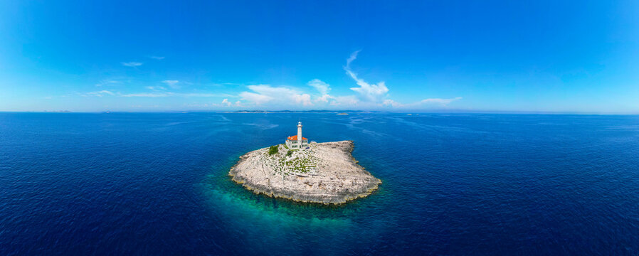 Aerial view of Blitvenica Lighthouse on a small rocky islet surrounded by the deep blue Adriatic Sea under a clear sky Zirje, Sibensko-kninska zupa, Croatia.