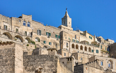 Obraz premium street view in the medieval city of Matera, Basilicata, Italy, featuring historic stone buildings, ancient architecture, under a clear blue sky in the UNESCO World Heritage 