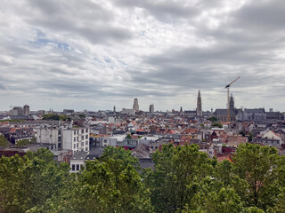 Fototapeta premium Antwerpen, België – Panoramic City Skyline with Cathedral Tower and Rooftops Under Cloudy Sky