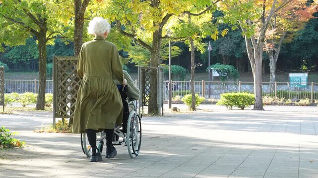 車椅子に乗った男性と介助する女性のシニアカップル