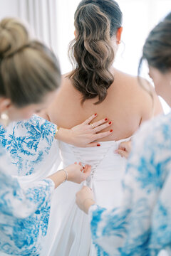 Bridal Preparation with Bridesmaids Adjusting Wedding Dress