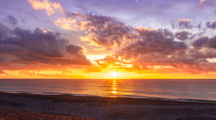 Obraz premium Dramatic seascape of sunset or sunrise sky with clouds during morning or evening. Dramatic sunset over the sea with orange clouds and sun above ocean water